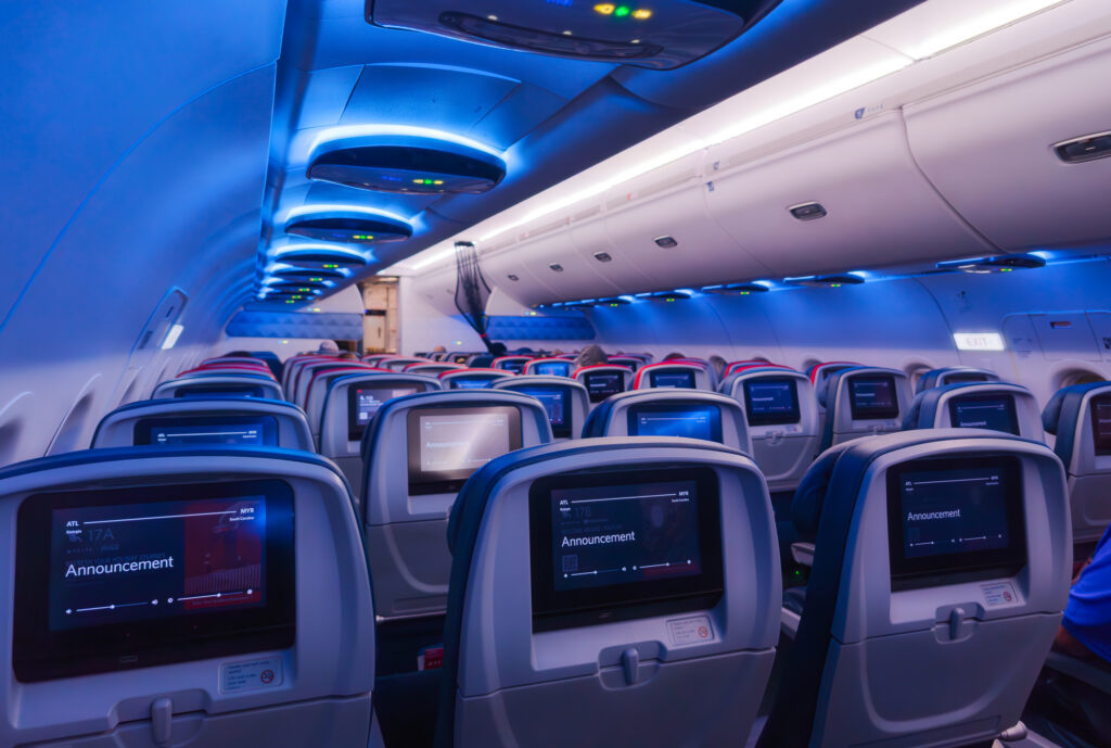 Interior view of an illuminated Delta Airlines Airbus A320 passenger cabin with an announcement in progress on the display screens in Atlanta, Georgia