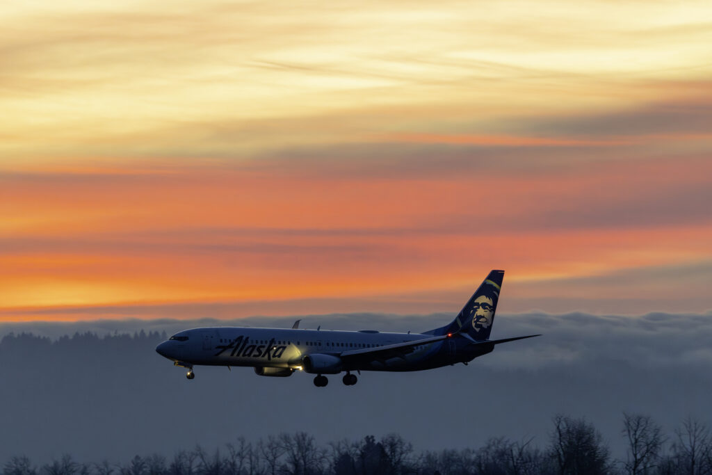 Portland, Oregon, USA - December 13, 2015: An Alaska Airlines 737 landing at Portland with a colorful sunset as a backdrop.