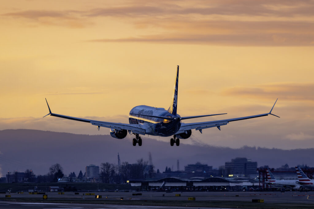 Portland, Oregon, USA - March 2, 2025: An Alaska Airlines Boeing 737 MAX 9 lands at Portland International Airport at sunset.