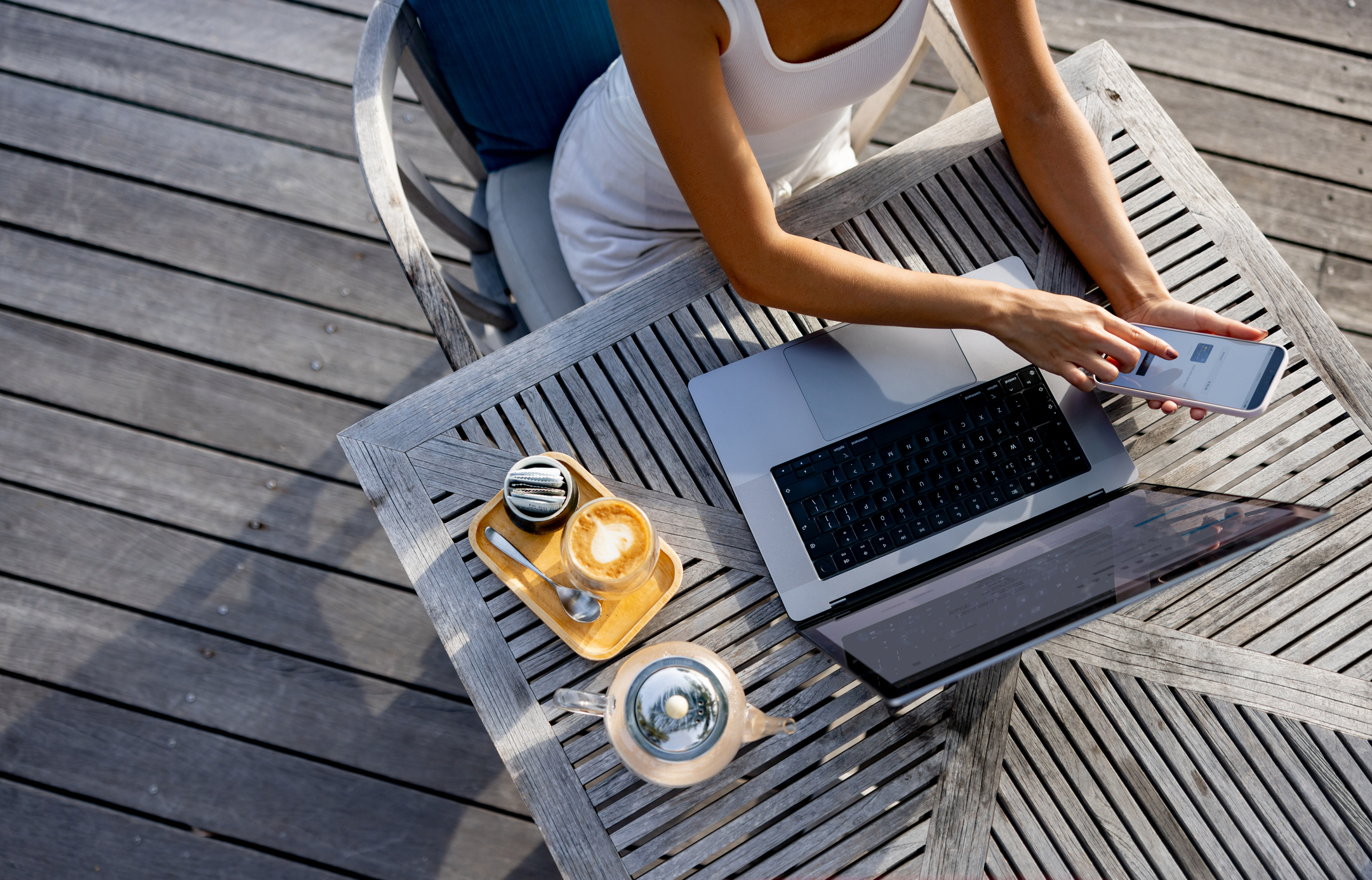 Close-up on a nomadic woman shopping online and using her cell phone to get an authentication code to confirm the transaction