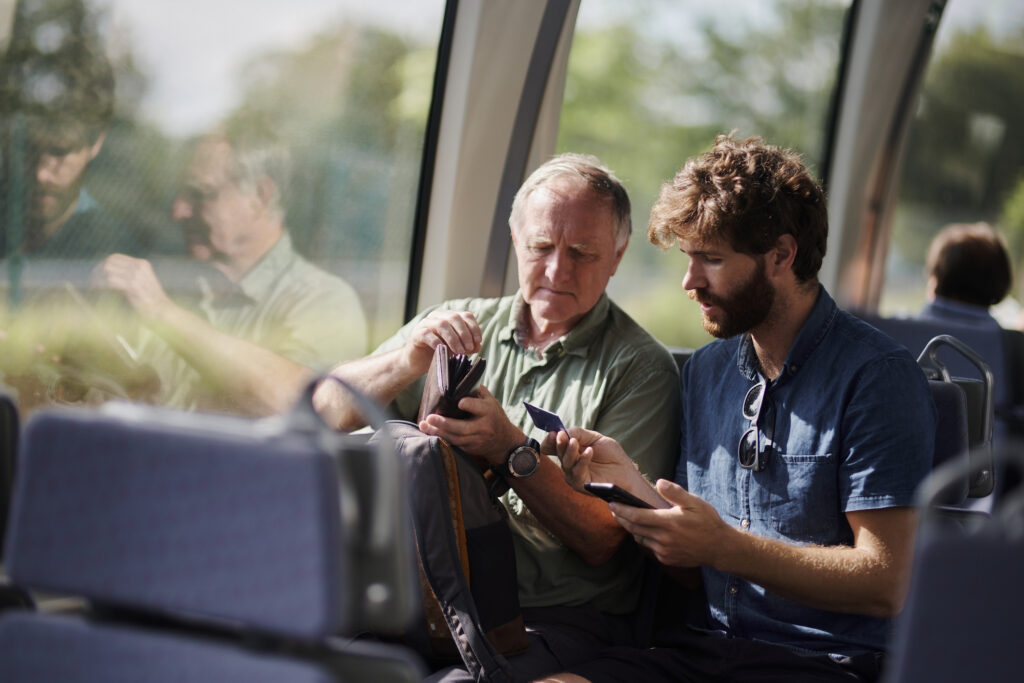 Train, travel and senior dad with man for journey, commute and passenger on metro transportation in city. Public transport, station and father with son on vehicle for trip, ride and adventure in town